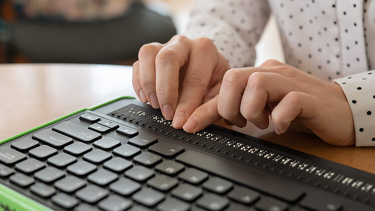 © Getty Images. Braillezeile Mensch tippt auf einer Braillezeile.